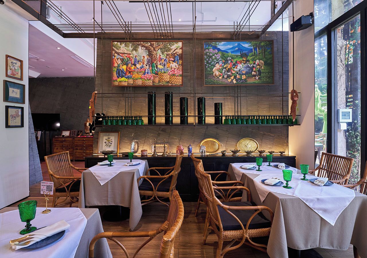 Een restaurant interieur met gedekte tafels, houten stoelen en kunstwerken aan de muren.