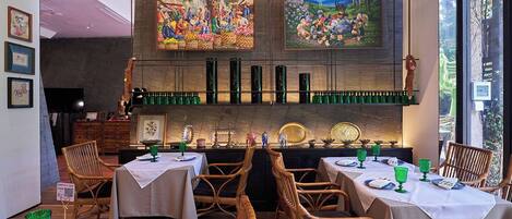Een restaurant interieur met gedekte tafels, houten stoelen en kunstwerken aan de muren.