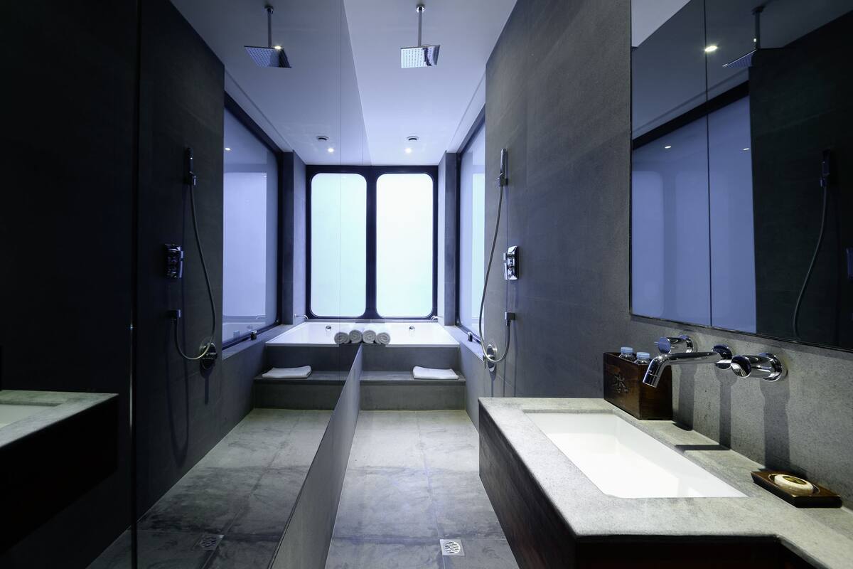 A modern bathroom with a large bathtub, two sinks, and a large mirror.