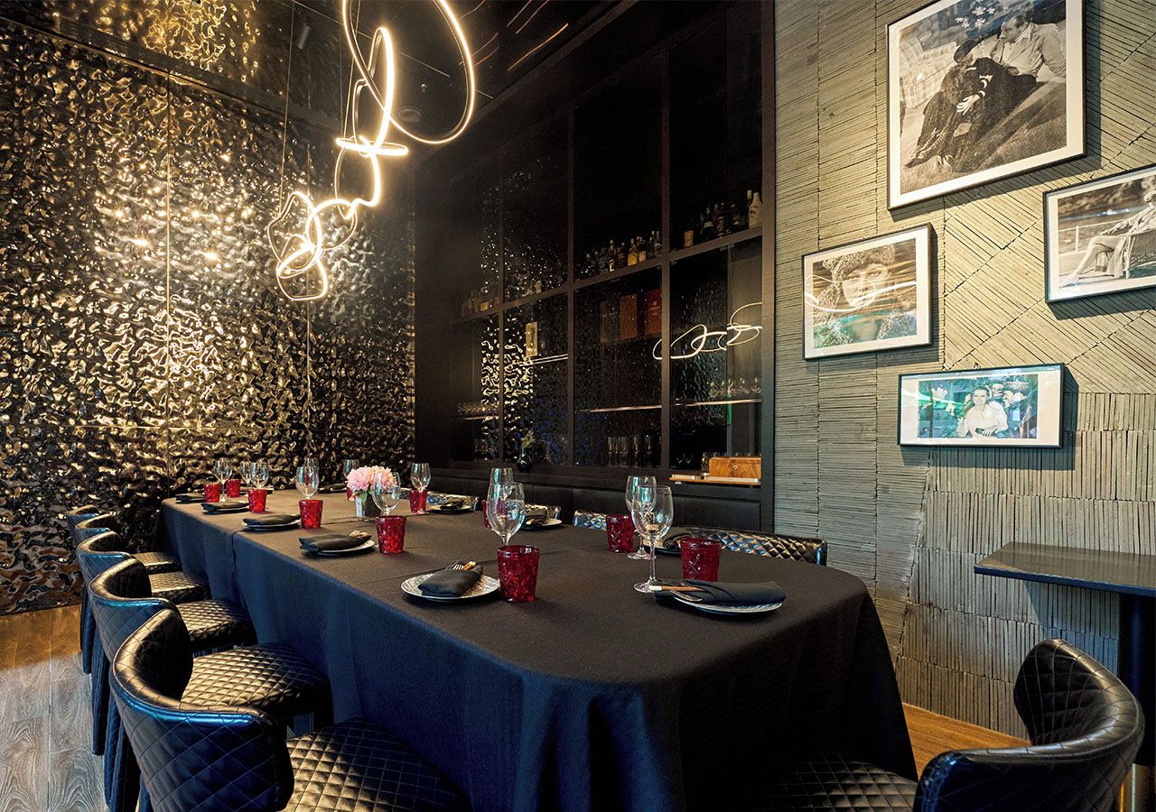 A restaurant with a long table set for dining, surrounded by chairs, and a wall with framed pictures.