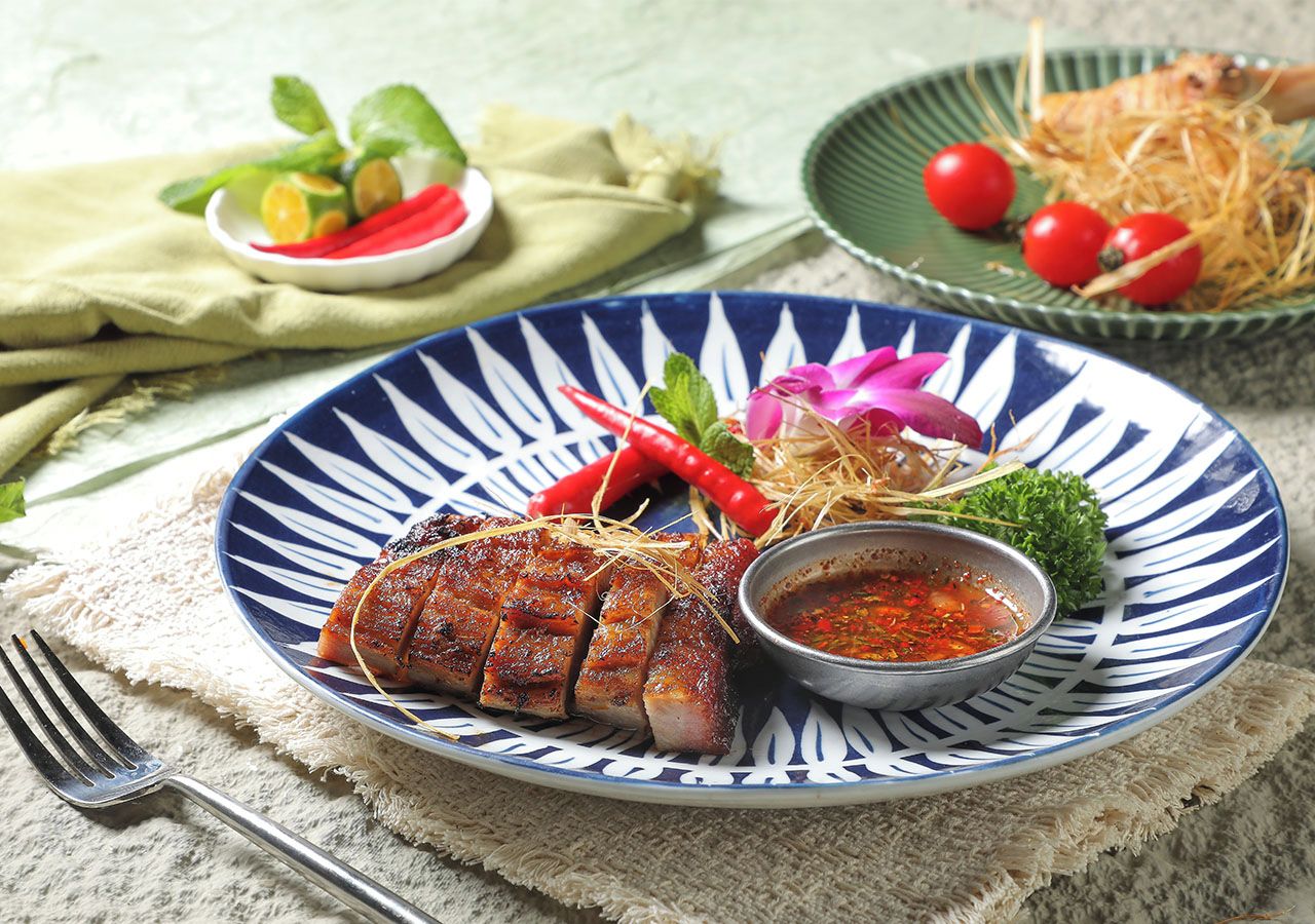 A plate of food with a sauce, garnished with herbs and chili peppers.