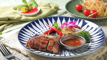 A plate of food with a sauce, garnished with herbs and chili peppers.