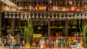 Eine Bar mit mehreren Regalen voller Spirituosenflaschen und zahlreichen Weingläsern, die von der Decke hängen.