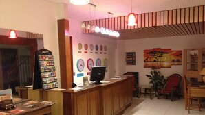 A reception area with a wooden desk, a computer, a clock display, and a wall with various clocks.