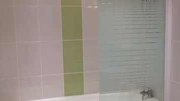 Une salle de bain équipée d’une baignoire, d’une douche et d’un espace de douche séparé par des parois en verre.