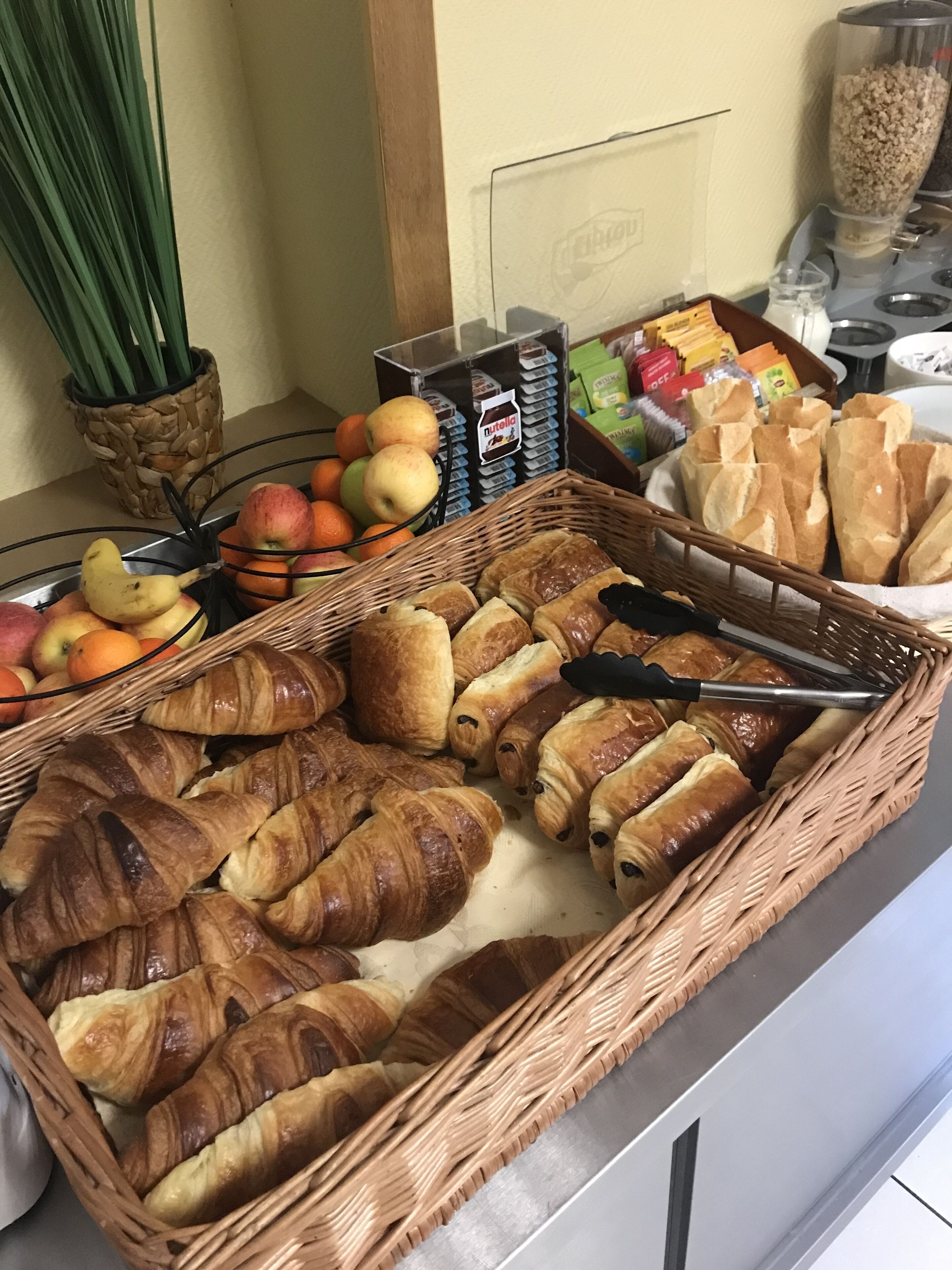 A breakfast buffet with croissants, fruits, and Nutella.