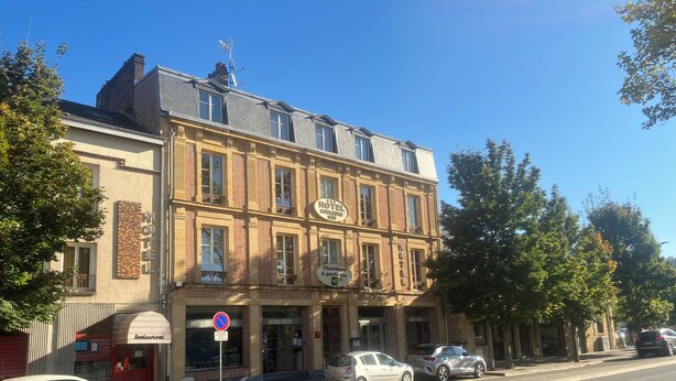 A hotel with a classic facade, multiple windows, and a sign indicating a restaurant.