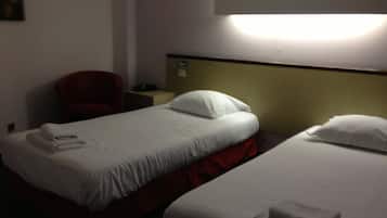 A hotel room with two beds, a chair, and a nightstand with a lamp.