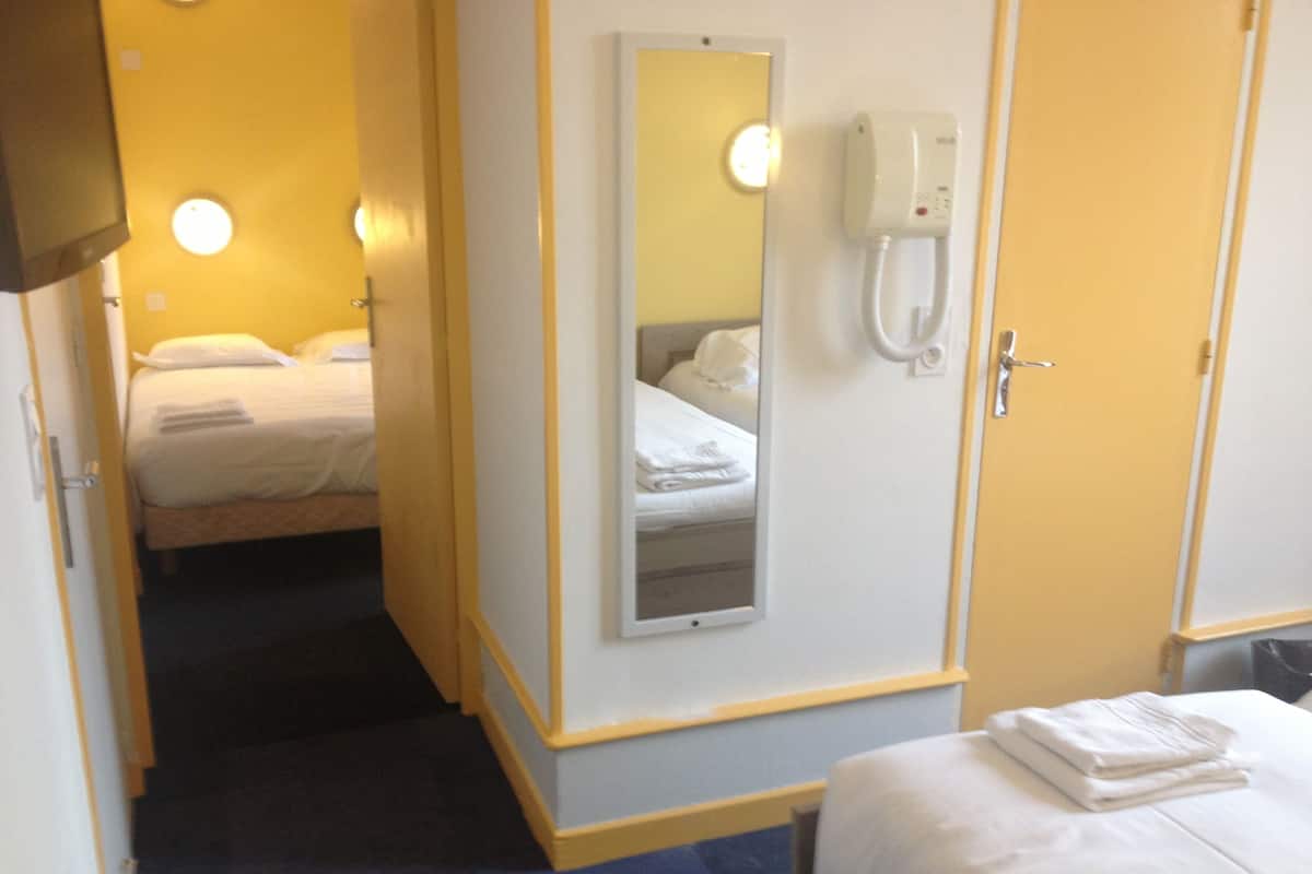 Une chambre d’hôtel avec un lit, une table de chevet, un miroir et un téléphone fixé au mur.