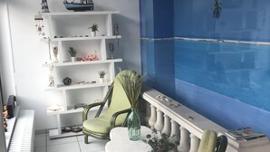 A modern living room with a piano, green chairs, a white coffee table, and a blue mural.