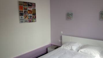 A hotel room with a bed, a nightstand, and a wall with various posters.