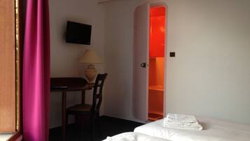 Une chambre d’hôtel avec un lit, un bureau et une chaise, une télévision et un placard ouvert.