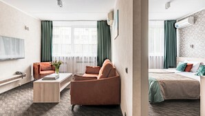 A hotel room with a sofa, a bed, a desk, and a TV. - Hotel Zemaites (Vilnius)
