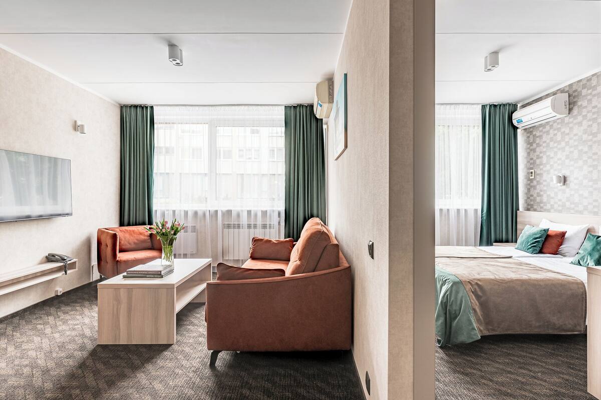 A hotel room with a sofa, a bed, a desk, and a TV.
