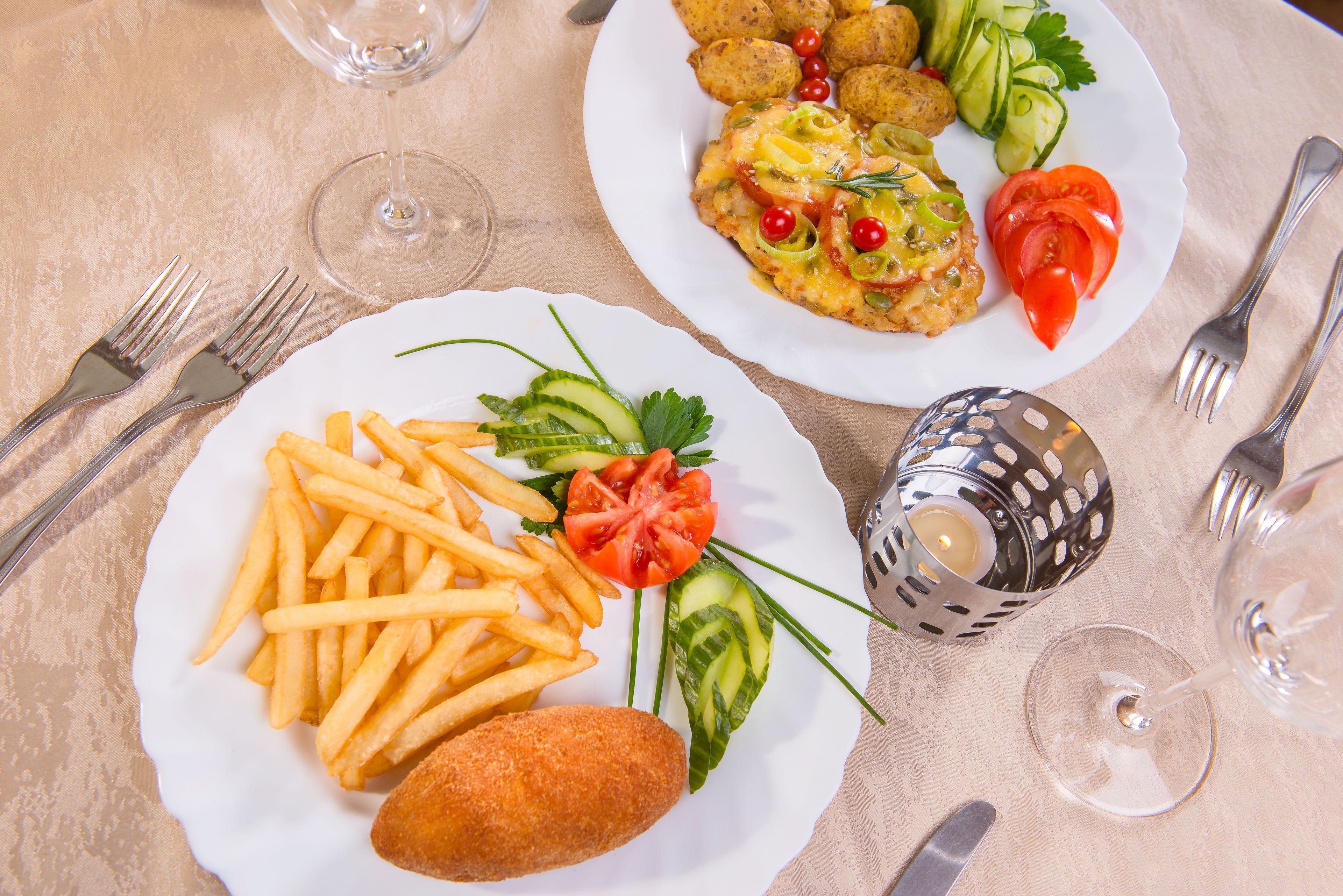 Two plates of food with a candle and wine glasses on a table.