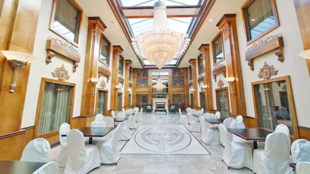A grand hotel lobby with a high ceiling, chandeliers, and a central aisle leading to a reception desk. - Woodbine Hotel and Suites (Toronto)