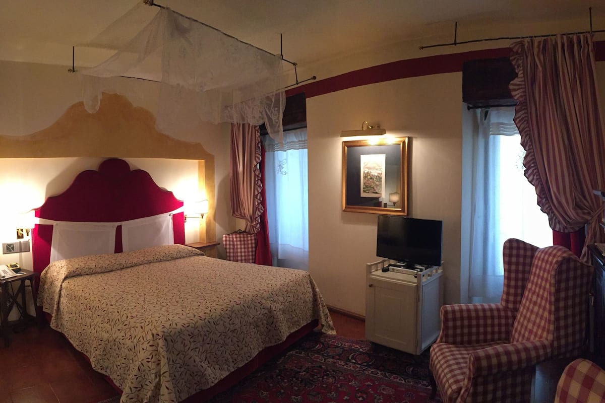 A hotel room with a bed, a television, a chair, and a small table.