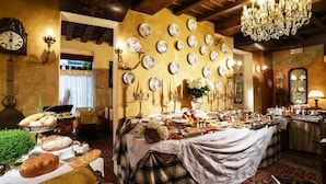 Un espace repas avec un buffet, agrémenté d’assiettes décoratives accrochées aux murs, d’un lustre et d’une horloge.
