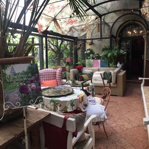 A cozy indoor garden with a table, chairs, and a sofa. - Hotel Gabbia d'Oro (Verona)
