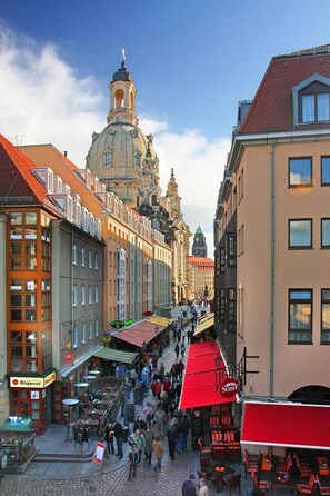 A bustling street with historic buildings, a prominent church tower, and outdoor seating areas. - Aparthotel Münzgasse (Dresden)