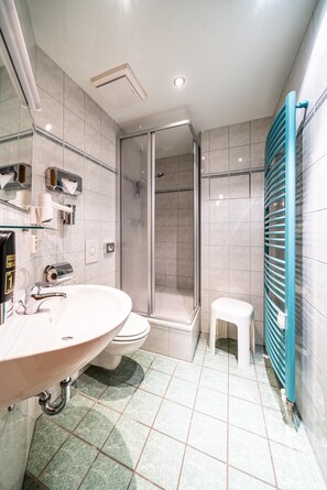 A modern bathroom with a large sink, toilet, and glass-enclosed shower. - Aparthotel Münzgasse (Dresden)