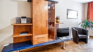 Habitación moderna con un mueble de madera, un televisor de pantalla plana, un sillón de cuero y una planta en maceta.