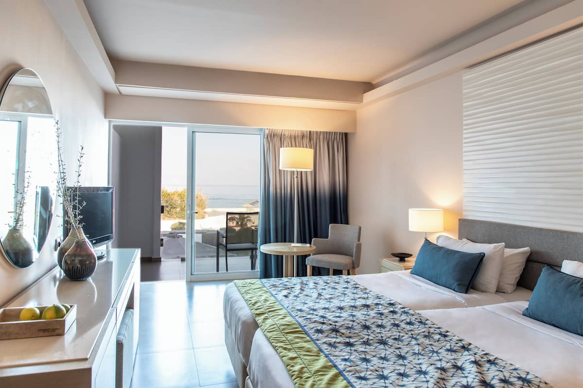Ein Hotelzimmer mit Bett, Schreibtisch, Stuhl, einem kleinen Tisch und einem Fenster mit Vorhängen.
