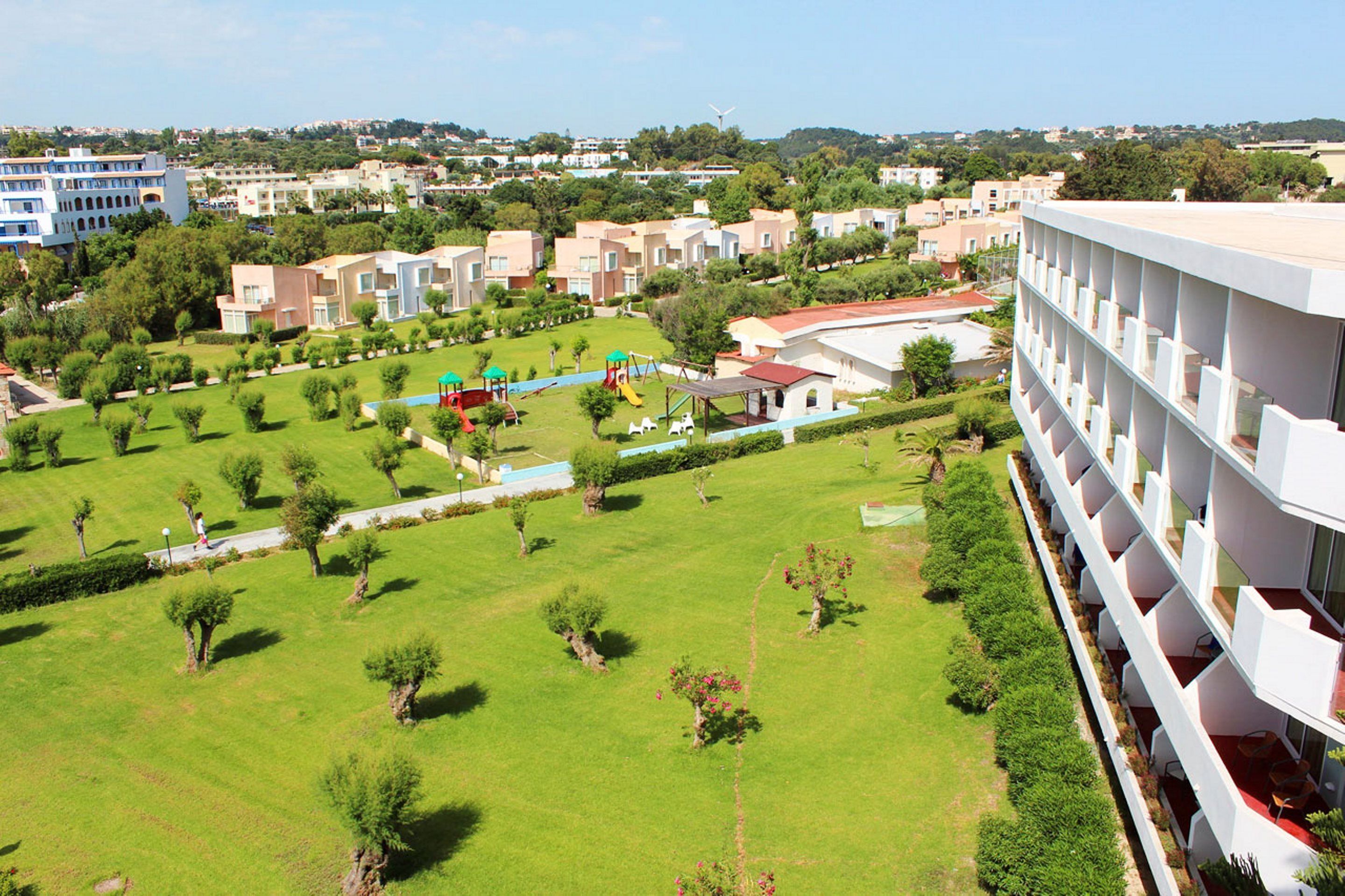 Zona residencial con edificios de apartamentos modernos, césped verde y un parque infantil.