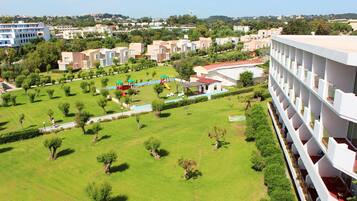 Zona residencial con edificios de apartamentos modernos, césped verde y un parque infantil.