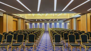 A conference room with rows of chairs, a patterned carpet, and a modern ceiling design.