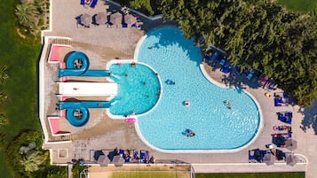 Enjoy a fun and inviting pool experience surrounded by lush greenery and comfortable lounge seating.