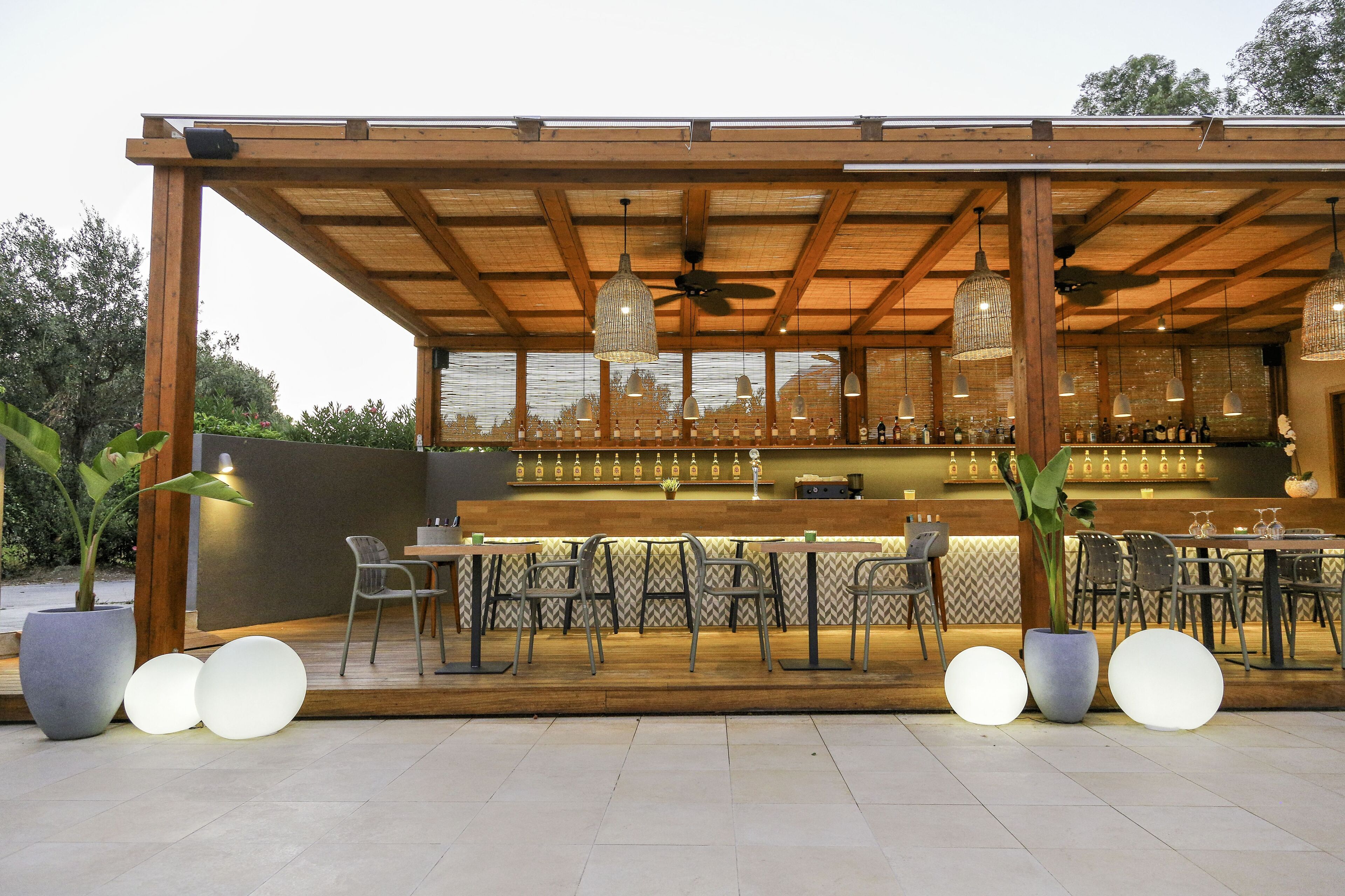 An outdoor bar area with wooden beams, hanging pendant lights, and a seating arrangement.