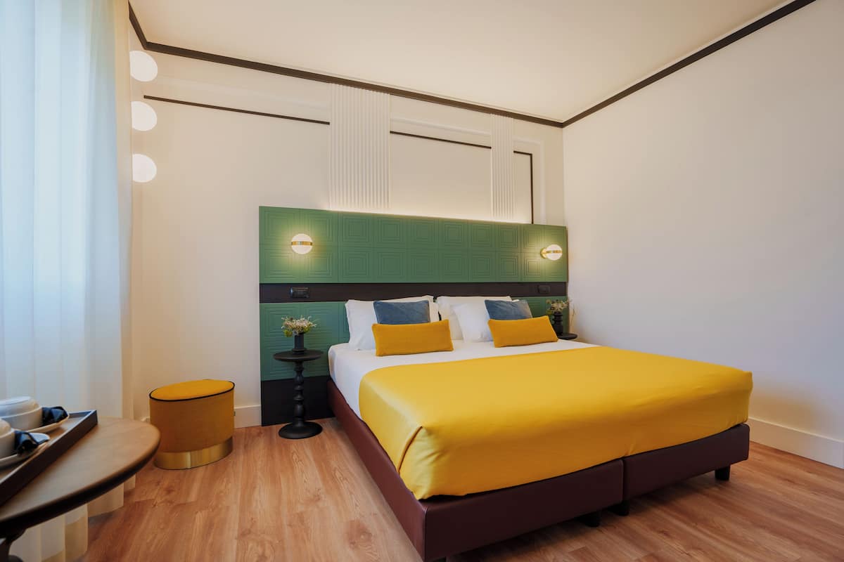A modern hotel room with a large bed, a small round table, and a nightstand.