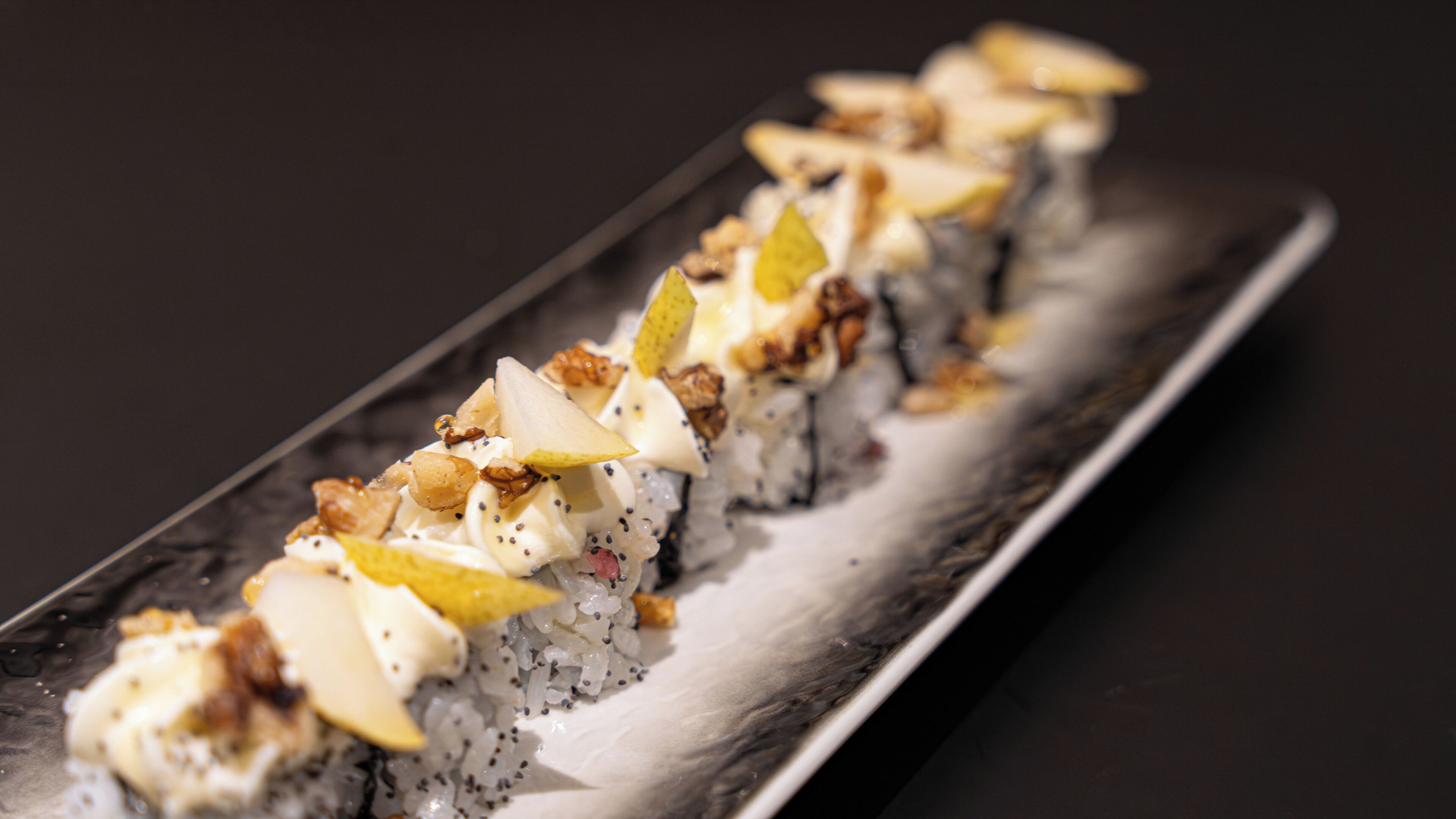Un plat de sushis, garnis de divers ingrédients, présenté sur une assiette rectangulaire.