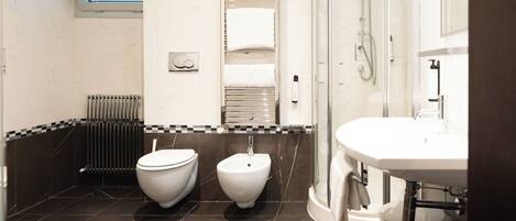 A modern bathroom with a bidet, a toilet, a shower, and a sink.