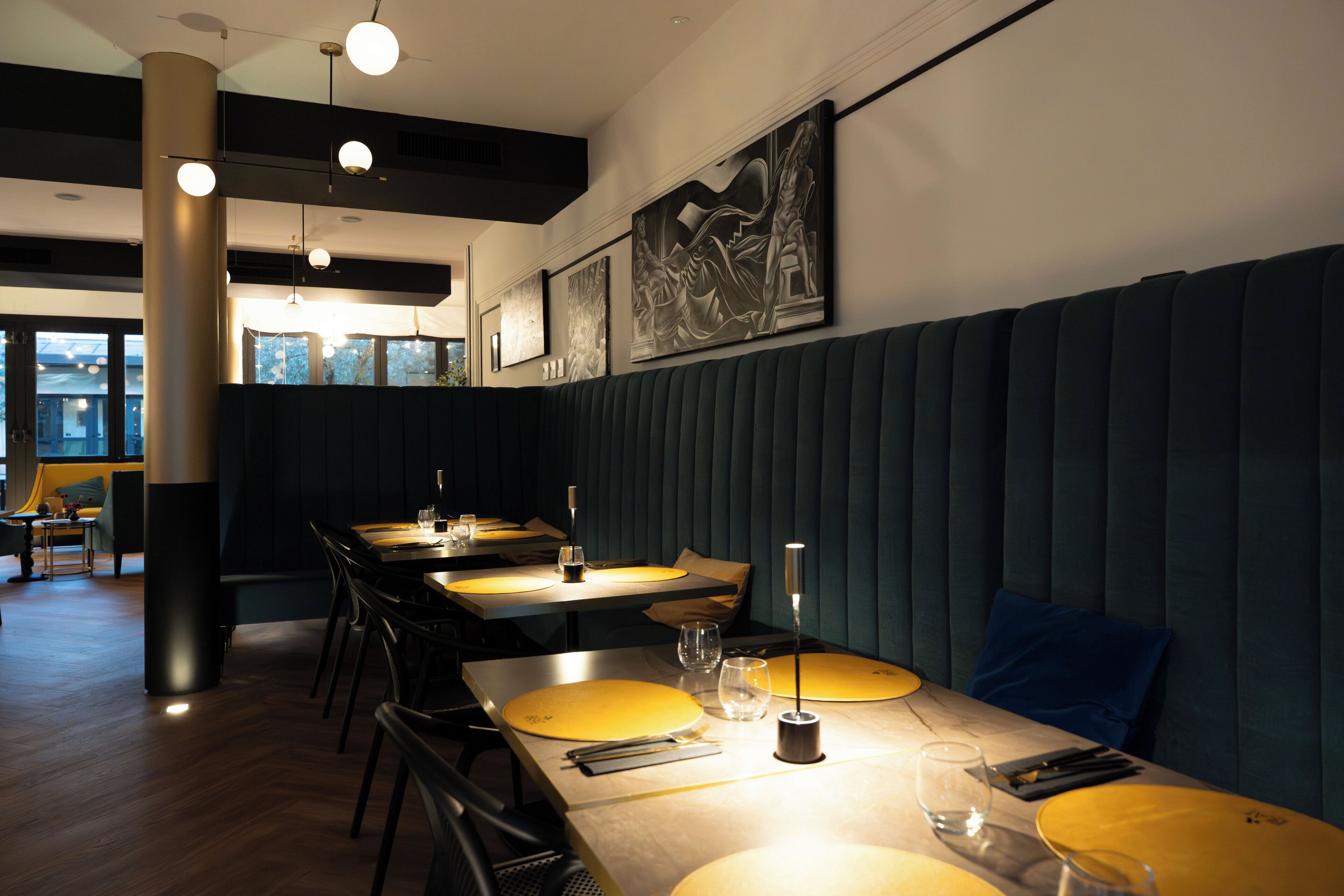 Ein Restaurantinneres mit Sitzecken, Tischen und Kunstwerken an den Wänden.