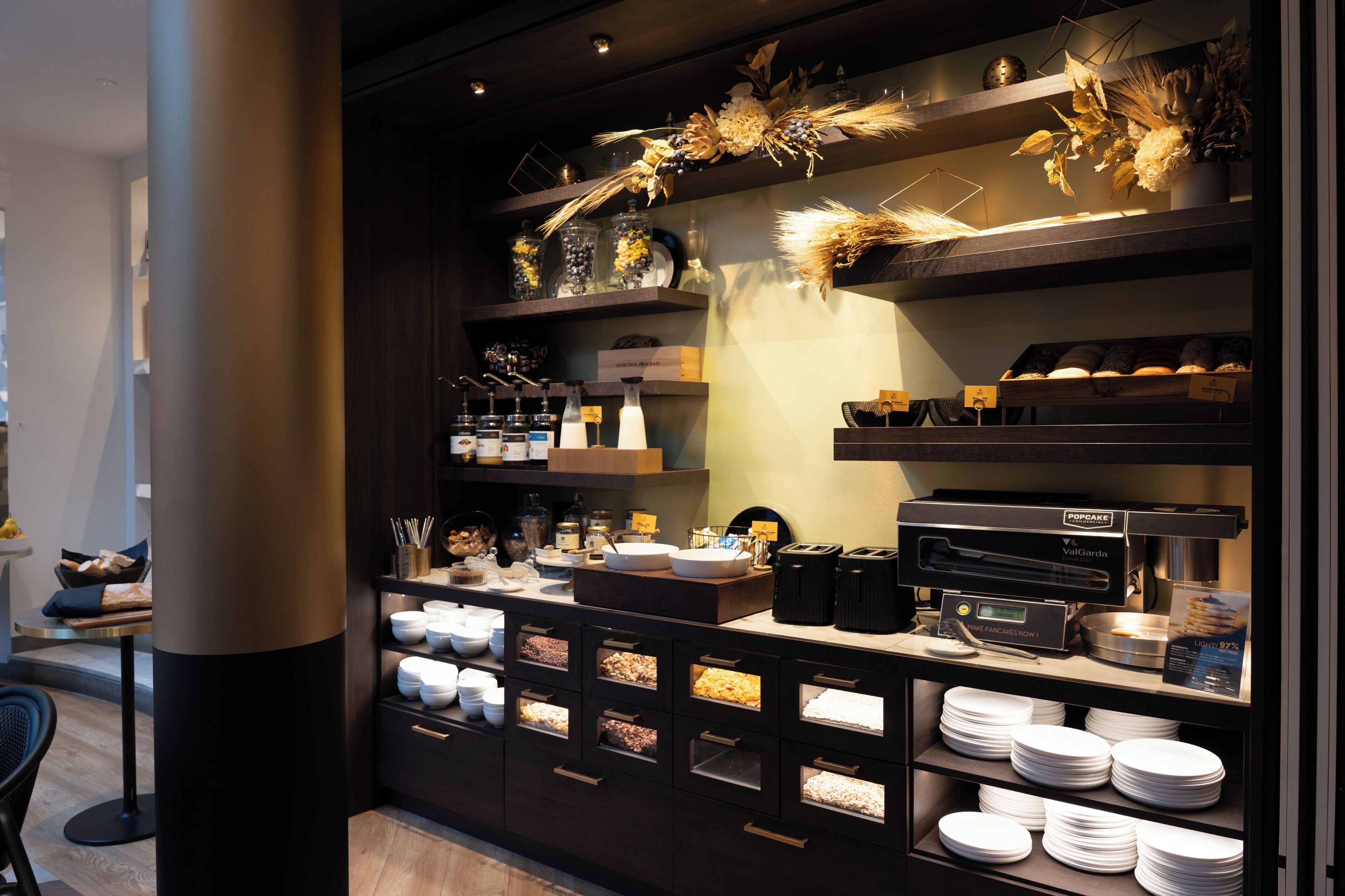 A buffet setup with various food items, a coffee machine, and decorative elements.