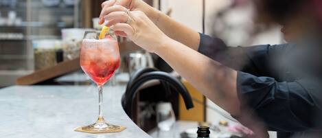 A person preparing a drink at a bar with a marble countertop and various bar tools.