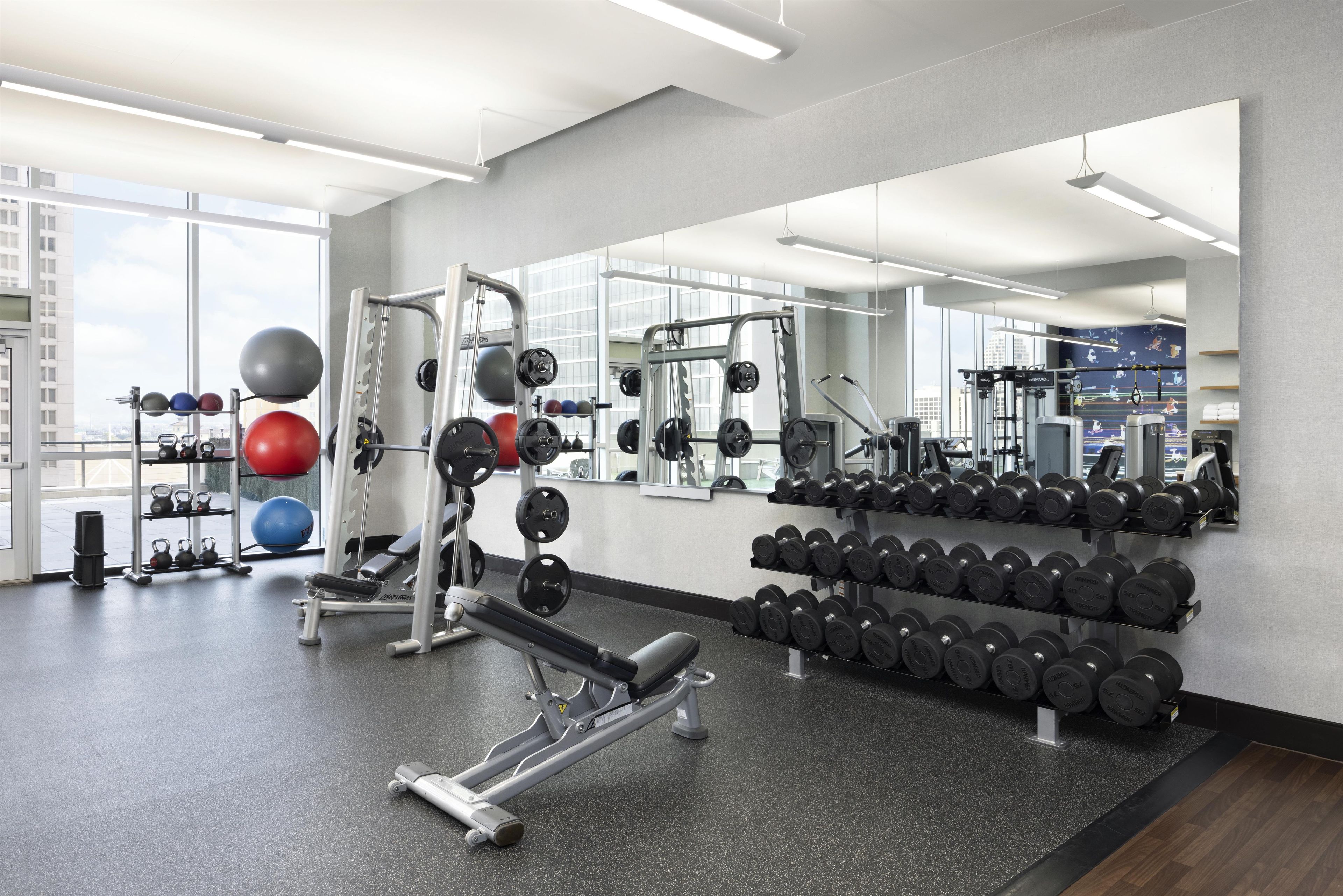 A gym with weightlifting equipment, exercise balls, and dumbbells.