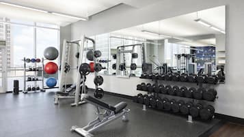 A gym with weightlifting equipment, exercise balls, and dumbbells.