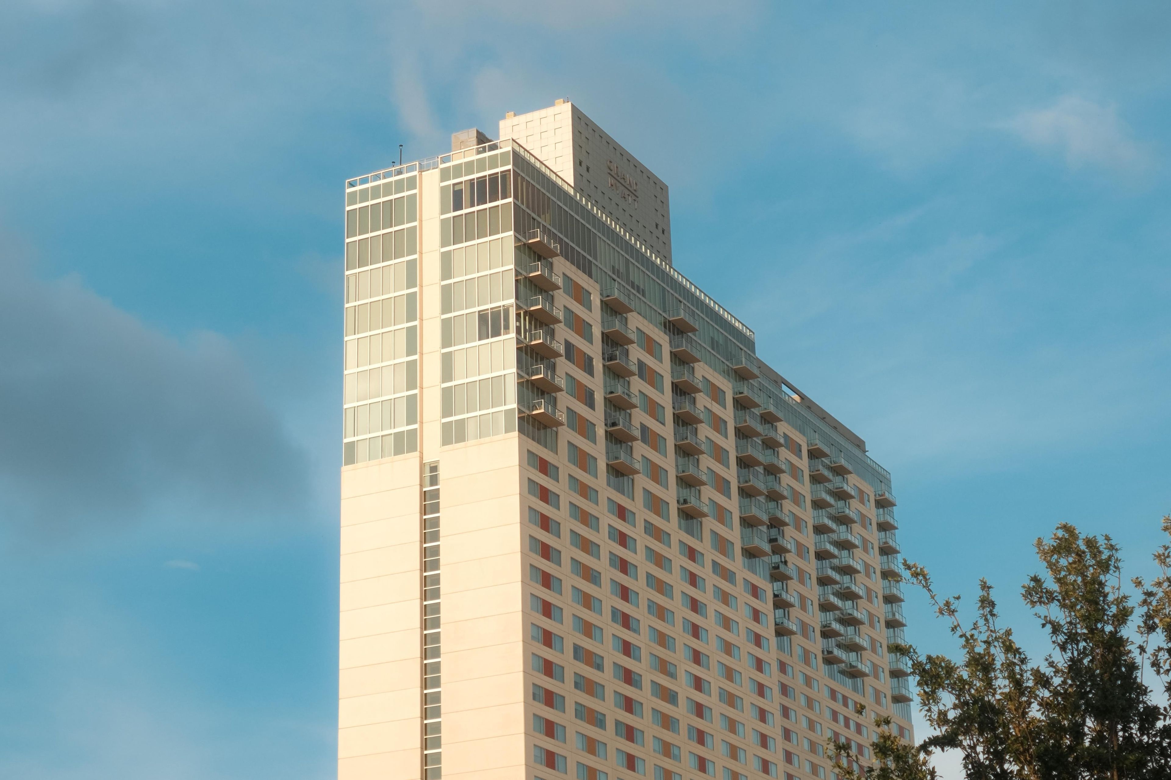 A high-rise building with a modern architectural design, featuring a prominent glass facade and a series of balconies.