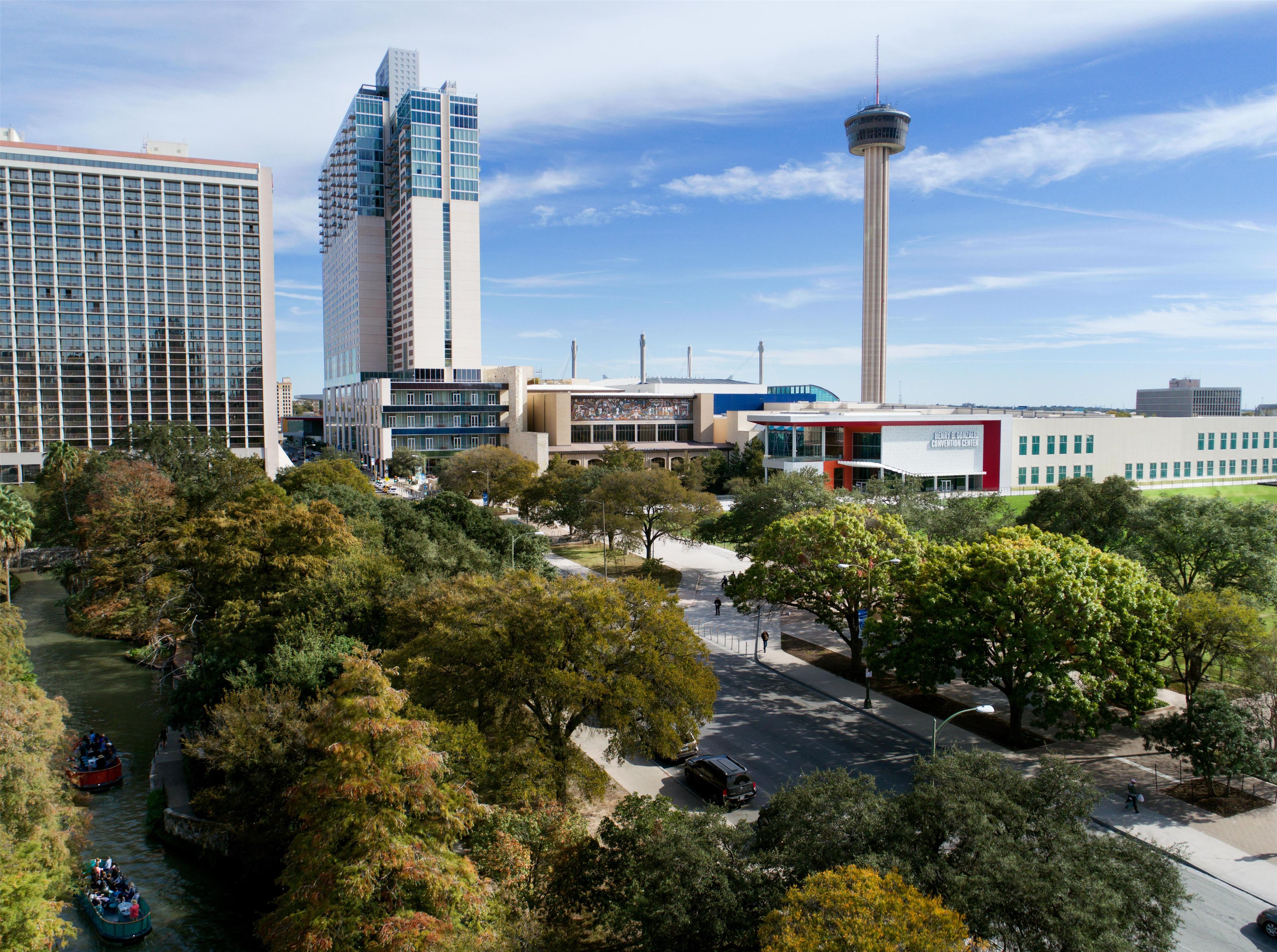 A cityscape with modern buildings, a tower, and a river with boats.