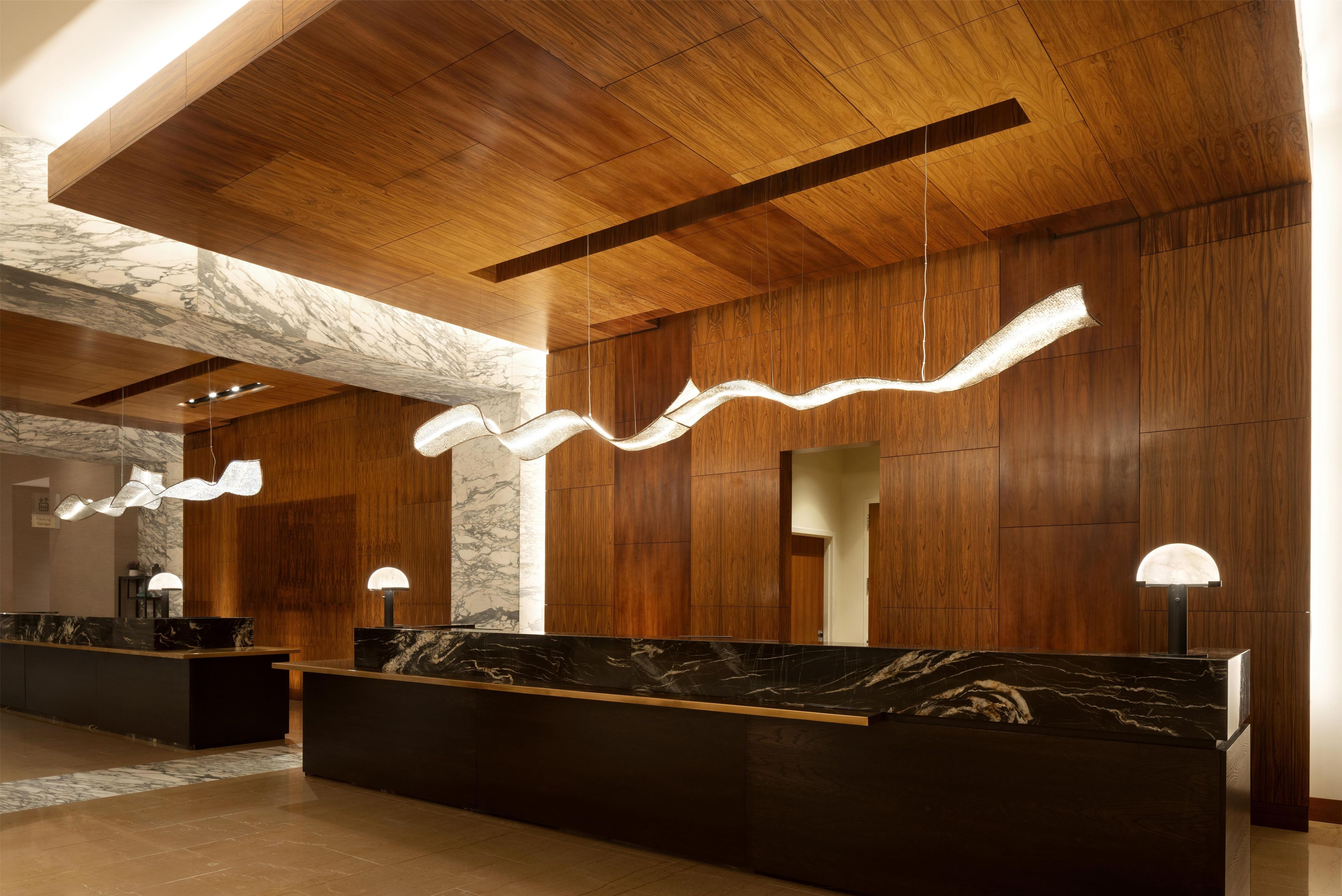 A reception area with marble countertops, wooden paneling, and modern pendant lighting.