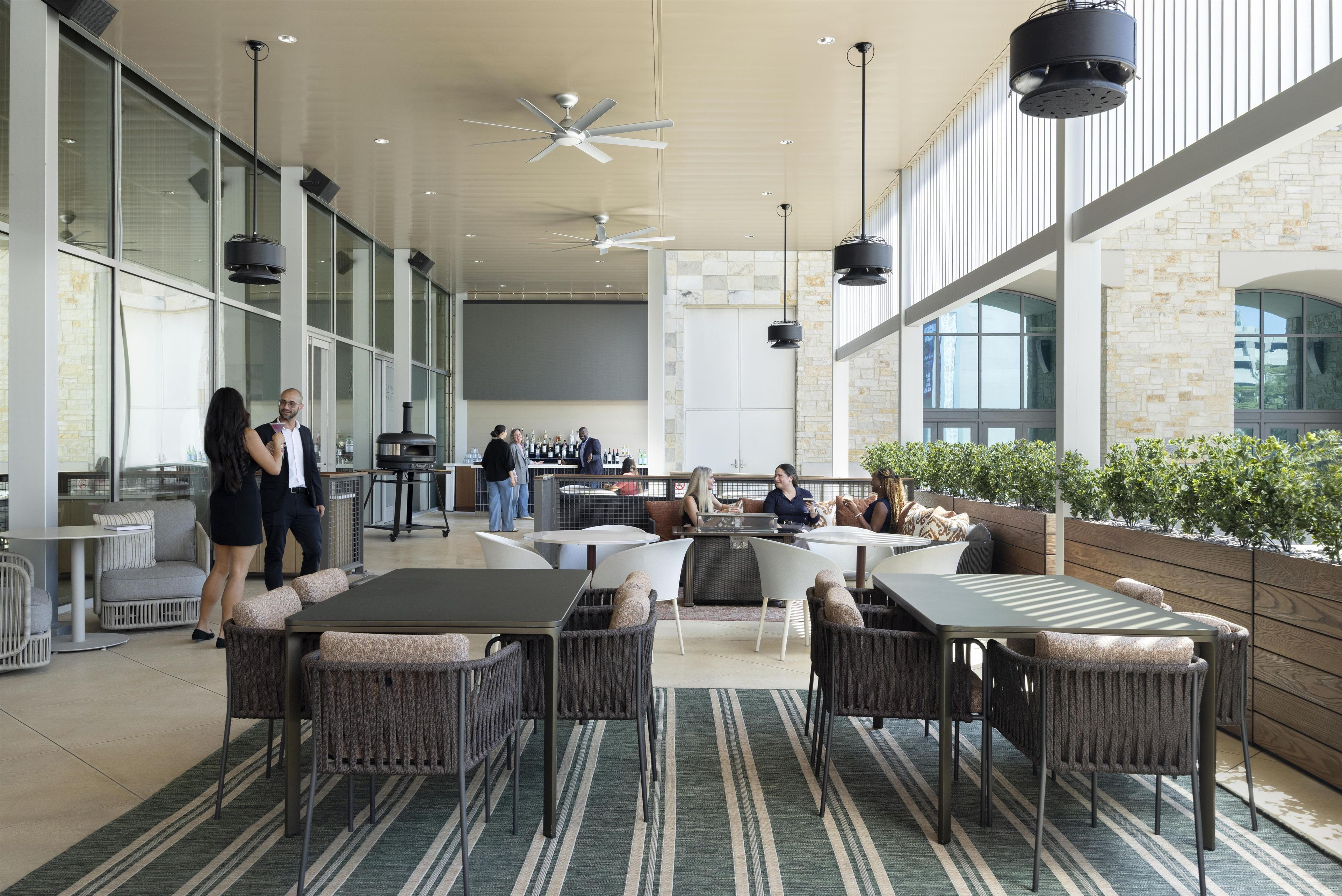 An indoor patio area with seating arrangements, a bar, and a large window providing natural light.