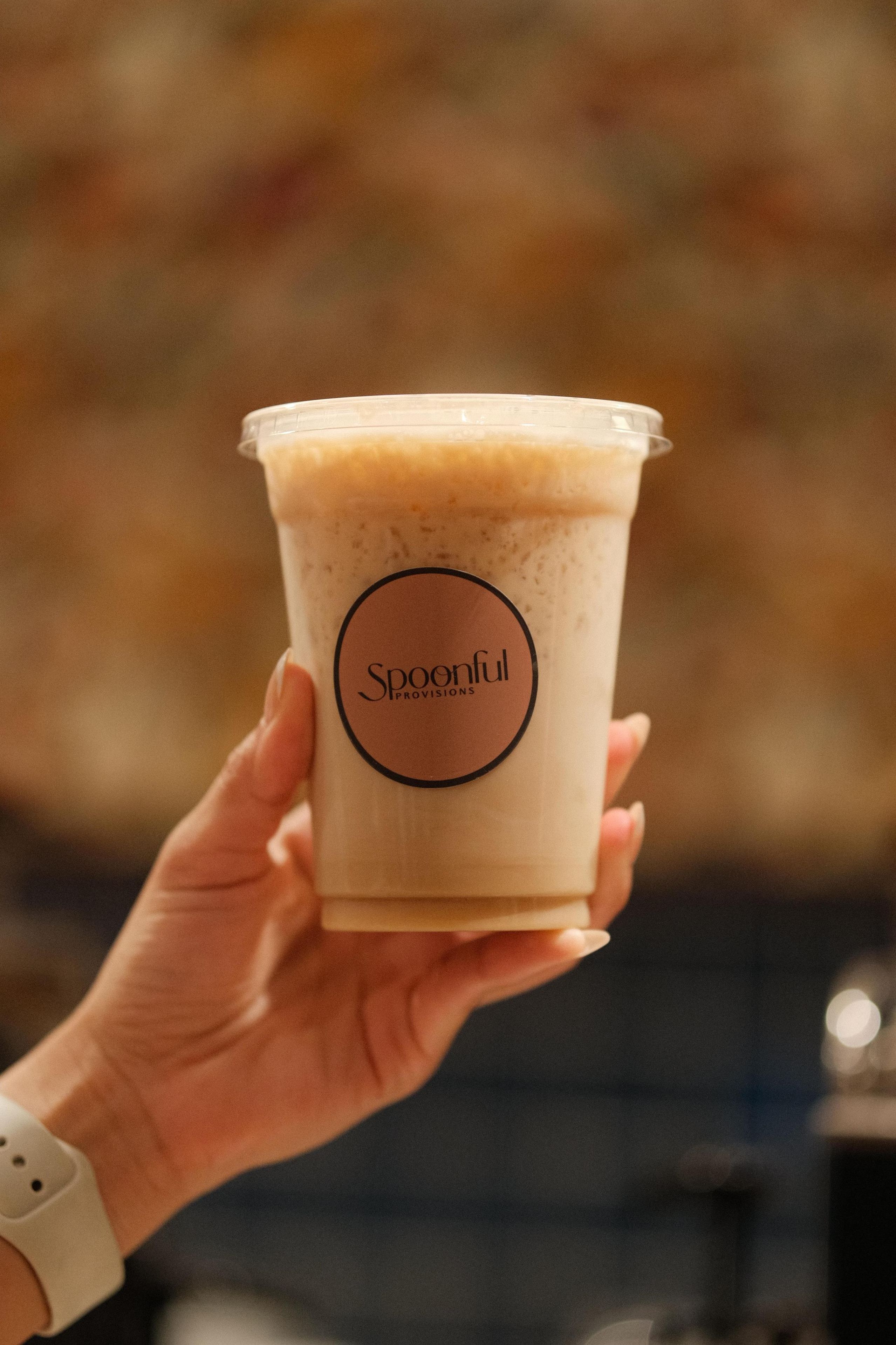 Eine Hand, die eine Tasse hält, mit dem Aufdruck 'Spoonful Provisions'.