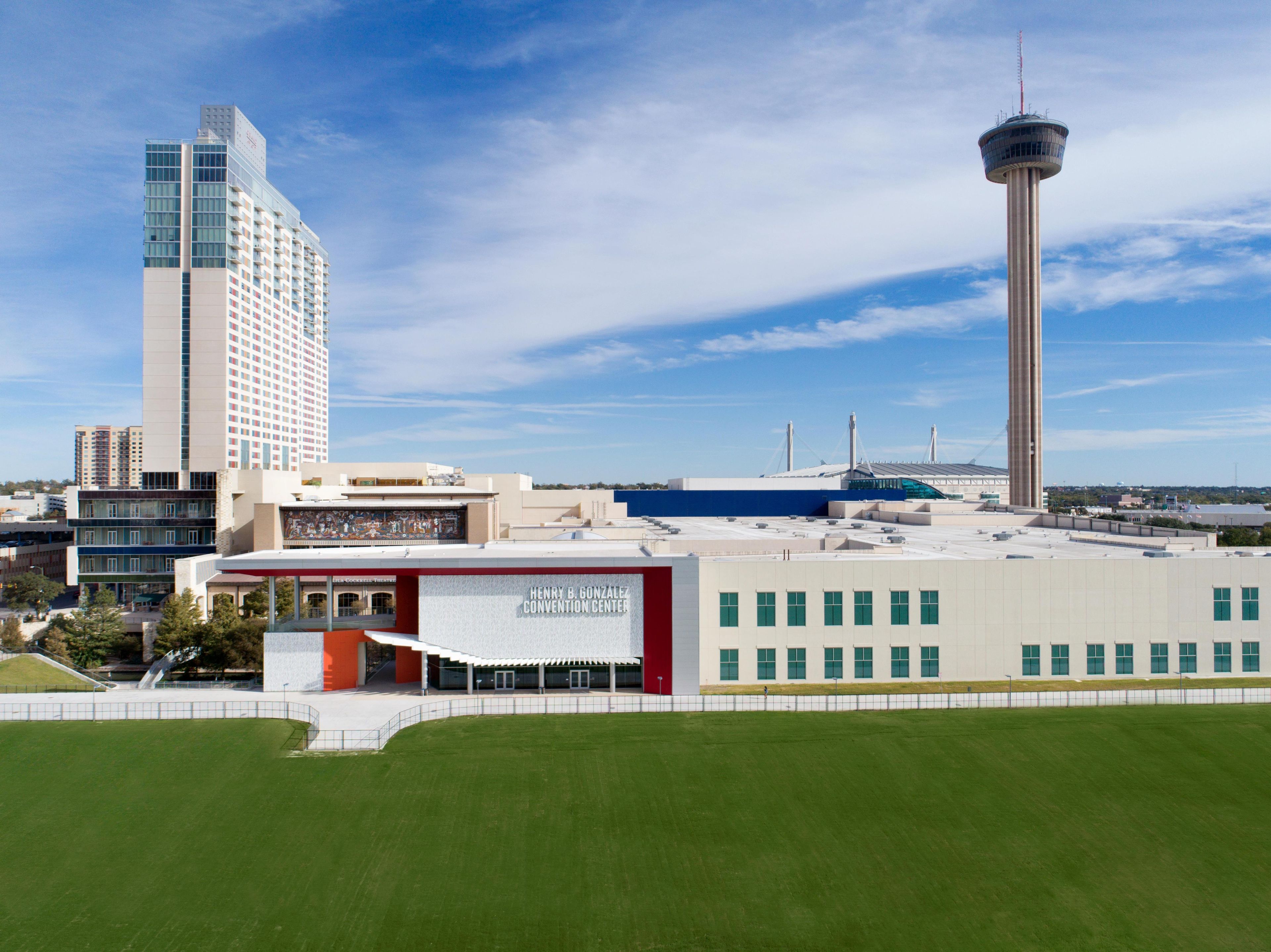 A convention center with a large open space, a tall tower, and a modern building with a glass facade.