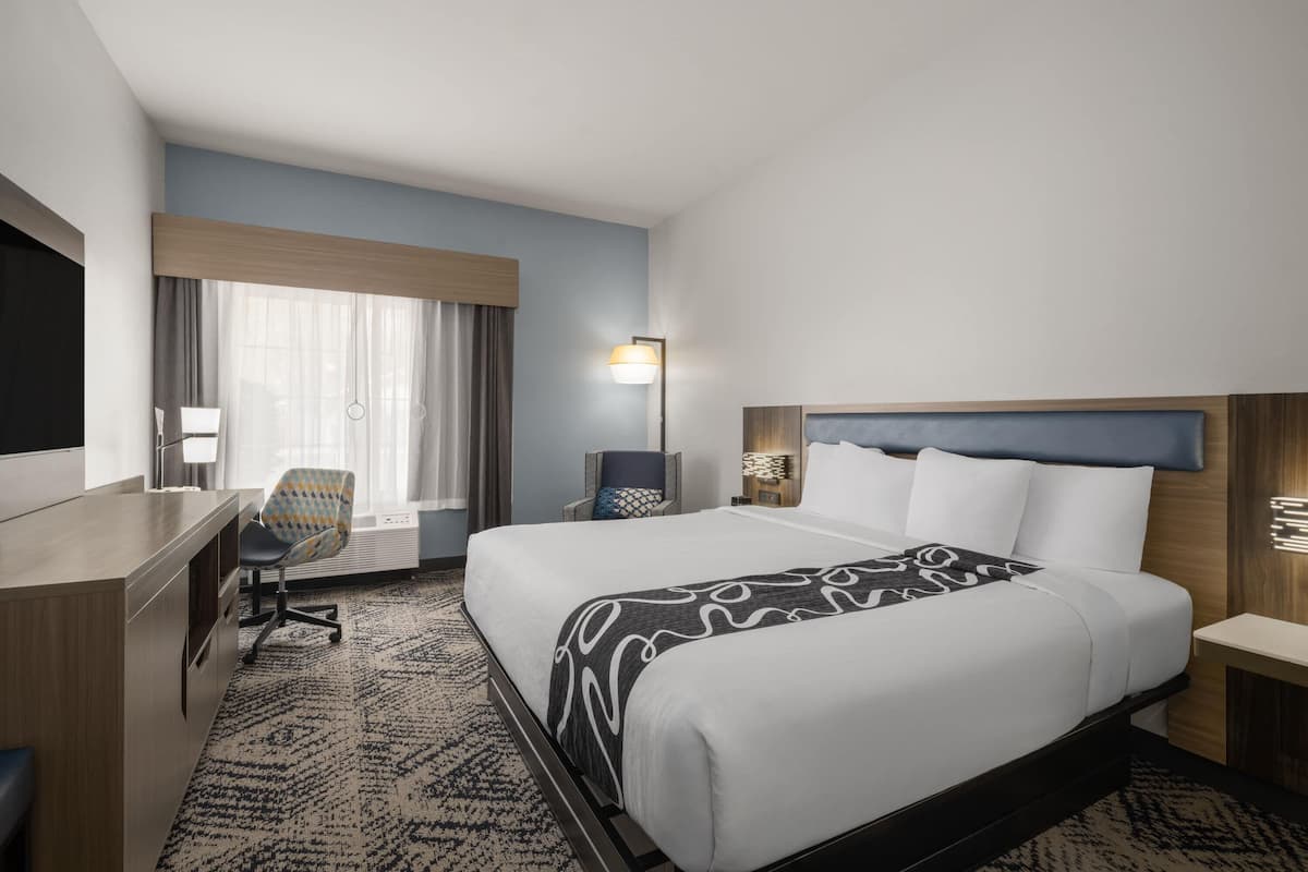 Una habitación de hotel con cama, escritorio, silla y lámpara.