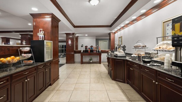 A hotel kitchen with wooden cabinets, a buffet setup, and a coffee station.