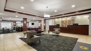 A spacious lobby with a reception desk, seating area, and a large window.