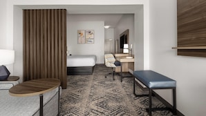 A hotel room with a bed, desk, chair, and a small table.